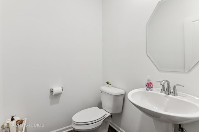 bathroom featuring a sink, baseboards, and toilet