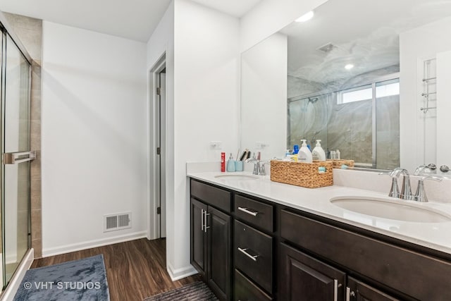 bathroom with a sink, a shower stall, wood finished floors, and visible vents