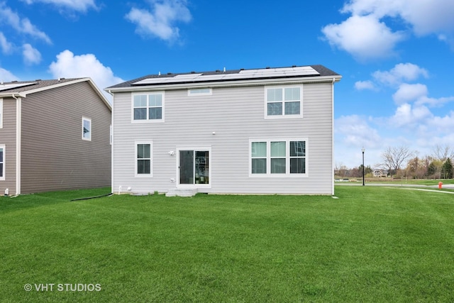 back of property featuring roof mounted solar panels and a yard