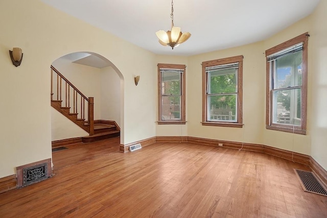 3945 W Dakin St, Chicago, IL 60618 - unfurnished room featuring light wood-type flooring, a chandelier, arched walkways, and stairs