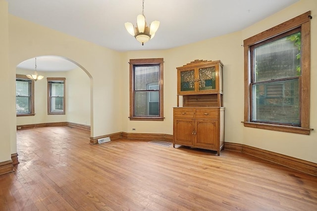 3945 W Dakin St, Chicago, IL 60618 - unfurnished dining area with a chandelier, arched walkways, and healthy amount of natural light