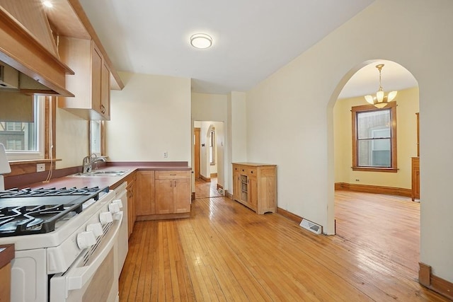 3945 W Dakin St, Chicago, IL 60618 - kitchen featuring white range with gas cooktop, arched walkways, light wood-style floors, and range hood