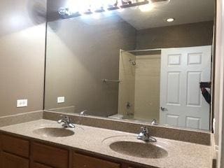 bathroom featuring double vanity, shower / bath combination, and a sink
