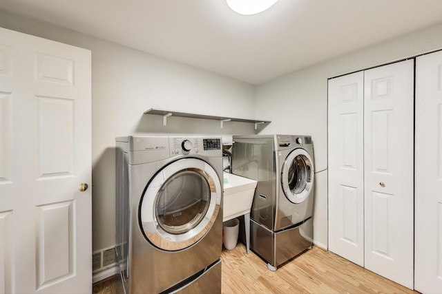 clothes washing area featuring separate washer and dryer, laundry area, and light wood-style floors
