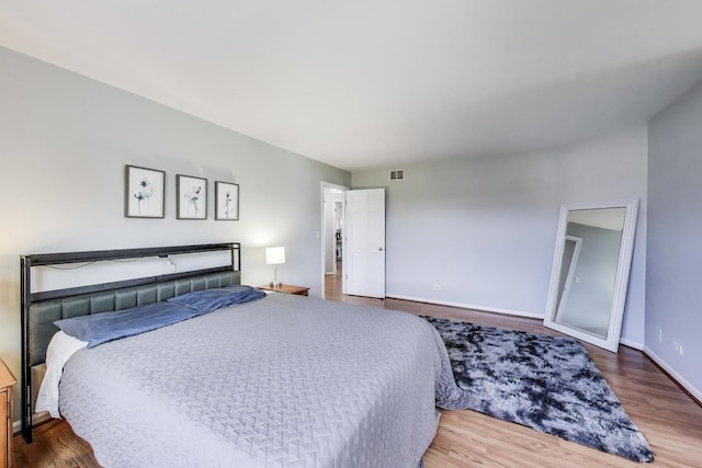 bedroom featuring baseboards, wood finished floors, and visible vents