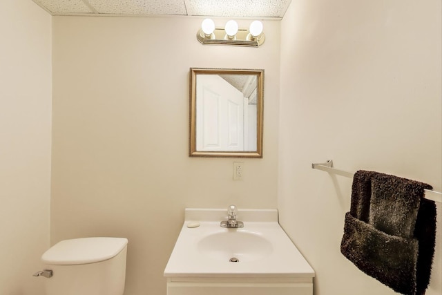 bathroom with toilet, a paneled ceiling, and vanity