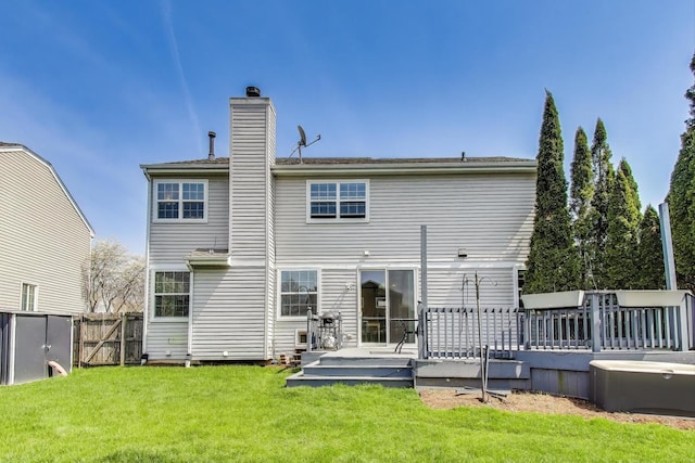 back of house featuring a lawn, a deck, fence, and a chimney