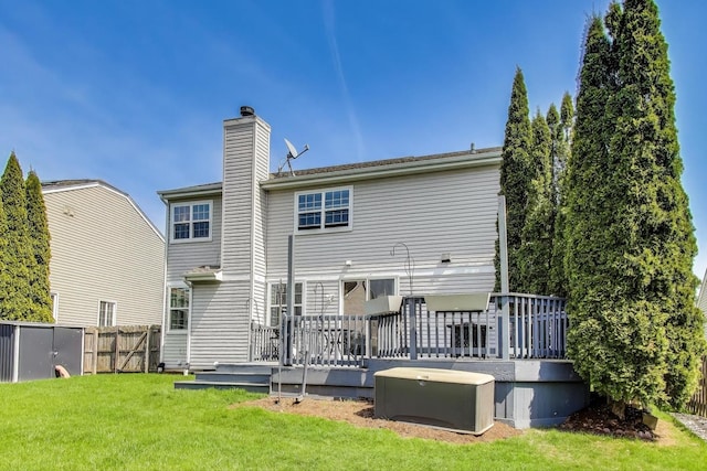 back of house with fence, a chimney, a lawn, and a deck