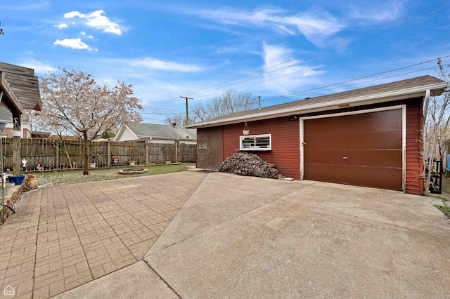 detached garage with fence and concrete driveway