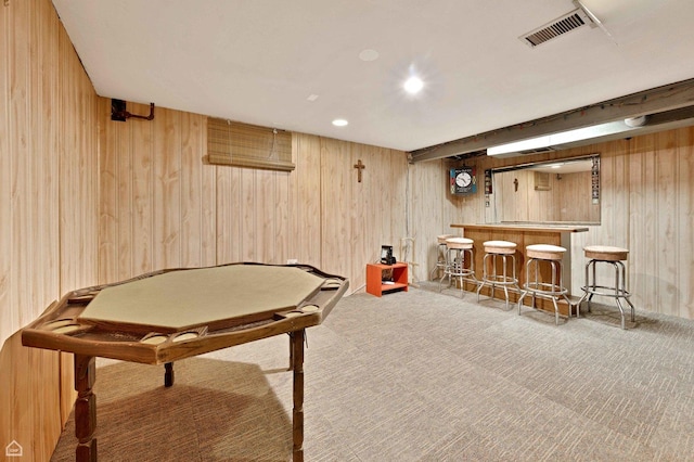 rec room with wooden walls, visible vents, a bar, and carpet