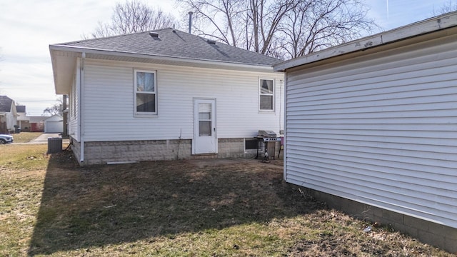 back of house featuring a shingled roof, a yard, and central AC unit