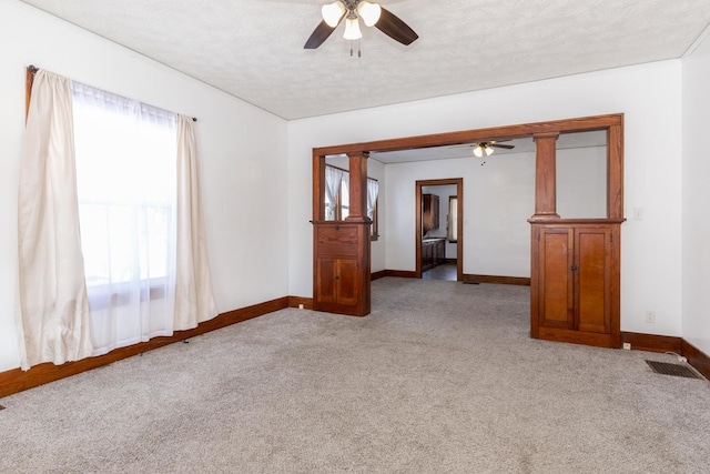 empty room featuring light carpet, a ceiling fan, and a healthy amount of sunlight