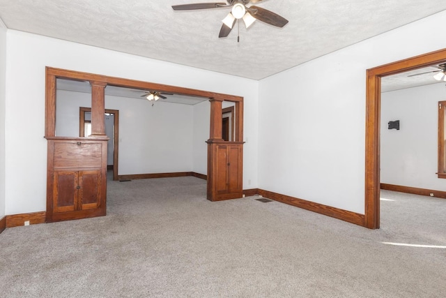 carpeted spare room featuring ceiling fan, baseboards, and a textured ceiling