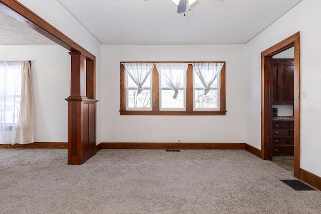 carpeted spare room with visible vents, a ceiling fan, and baseboards