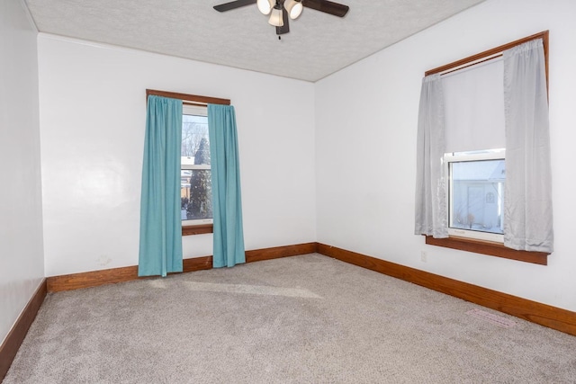 carpeted empty room featuring baseboards, a ceiling fan, and a textured ceiling