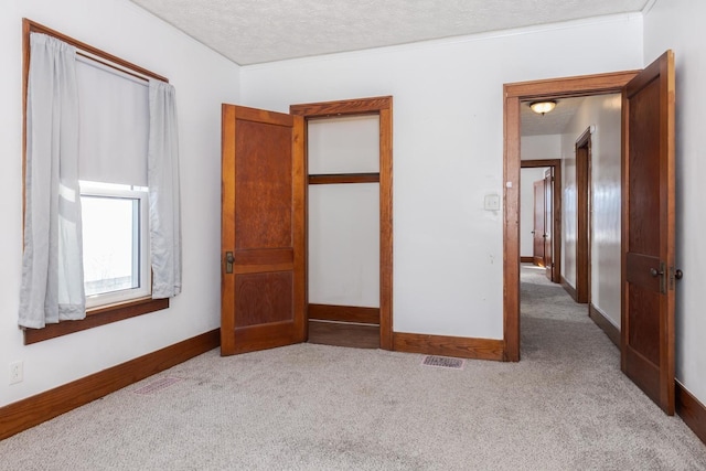 unfurnished bedroom featuring visible vents, baseboards, carpet floors, and a textured ceiling