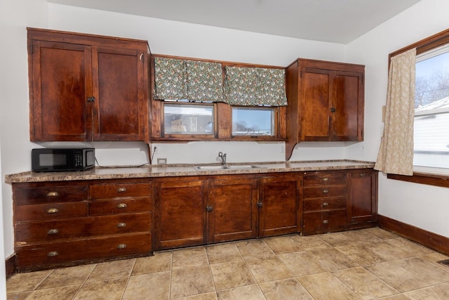 kitchen with black microwave, a sink, and baseboards