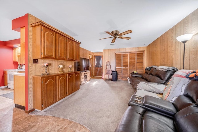living area with ceiling fan and wooden walls