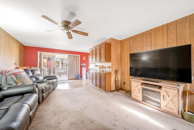 living area featuring light colored carpet, ceiling fan, and wood walls