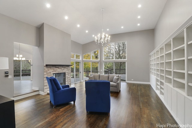 living room with a chandelier, a fireplace, a towering ceiling, and dark wood-type flooring