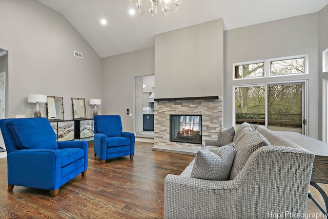living area featuring wood finished floors, visible vents, a multi sided fireplace, high vaulted ceiling, and a notable chandelier