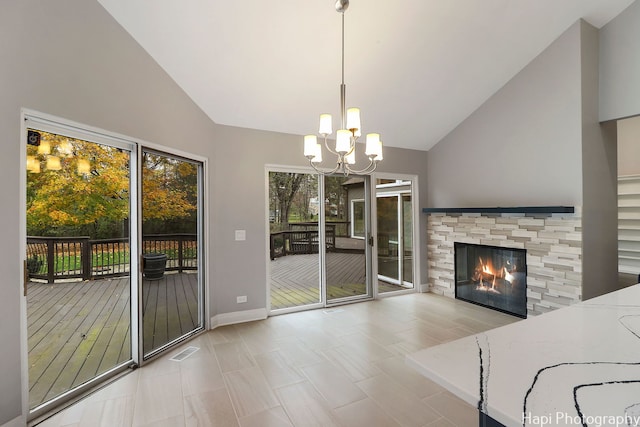 unfurnished dining area featuring a chandelier, visible vents, baseboards, a fireplace, and high vaulted ceiling
