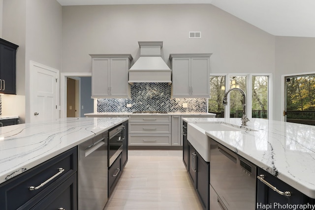 kitchen with custom exhaust hood, high vaulted ceiling, backsplash, and visible vents