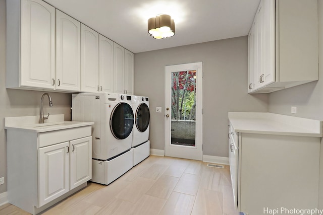laundry room with visible vents, baseboards, a sink, cabinet space, and washing machine and clothes dryer