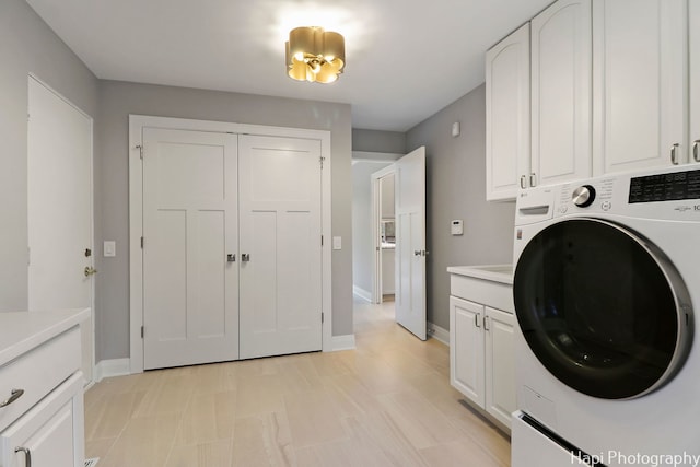 washroom featuring baseboards, washer / clothes dryer, and cabinet space