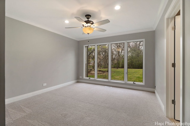 spare room with crown molding, carpet flooring, baseboards, and a ceiling fan