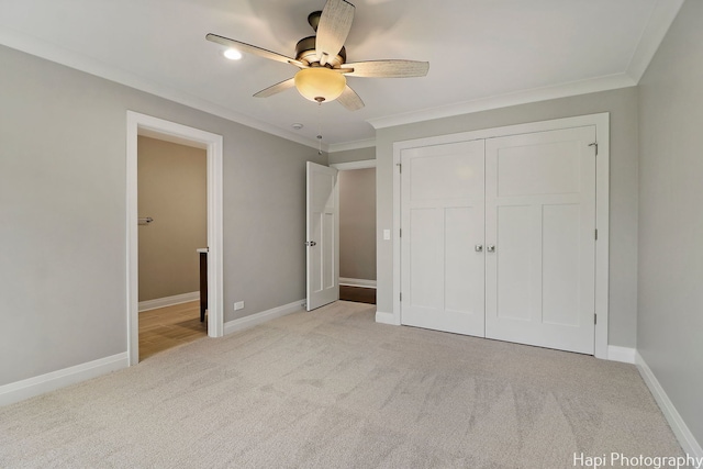 unfurnished bedroom featuring light carpet, baseboards, a closet, and crown molding