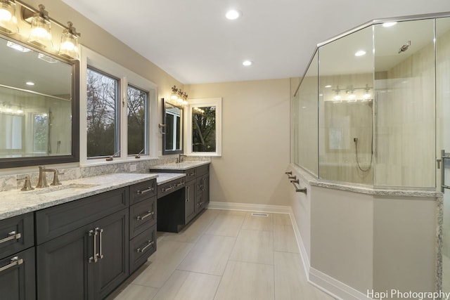 bathroom with a walk in shower, vanity, baseboards, and recessed lighting
