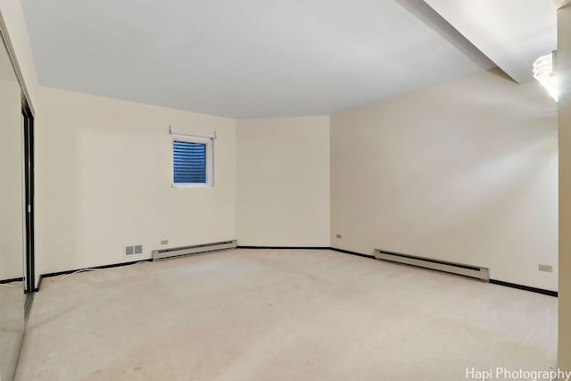 carpeted spare room featuring a baseboard heating unit, baseboards, baseboard heating, and visible vents
