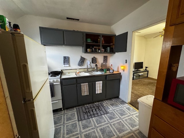 kitchen with a sink, visible vents, light floors, white appliances, and open shelves