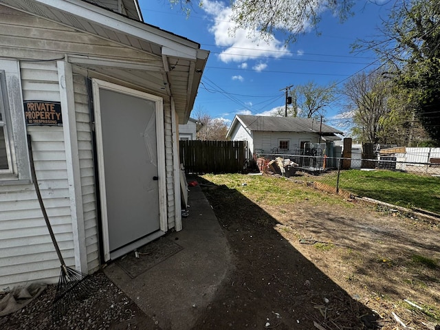 view of side of home featuring fence and an outbuilding