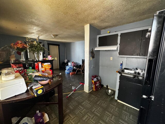 kitchen featuring black refrigerator with ice dispenser, a textured ceiling, and a sink