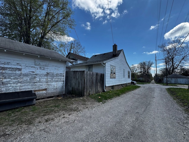 view of home's exterior featuring a chimney and fence