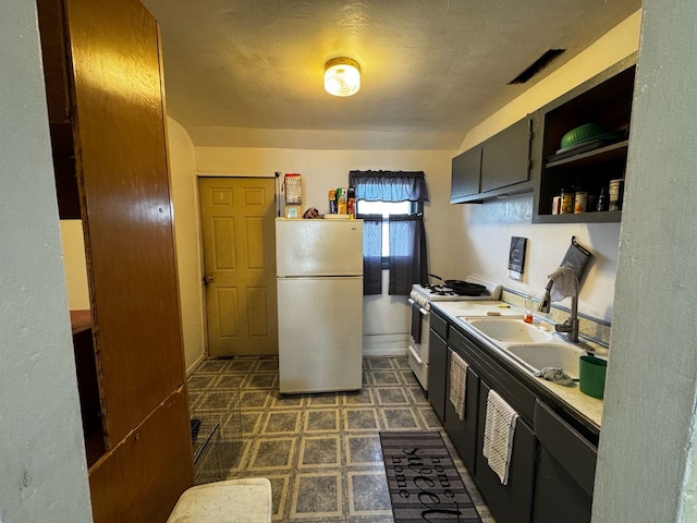 kitchen with a sink, white appliances, open shelves, dark floors, and light countertops
