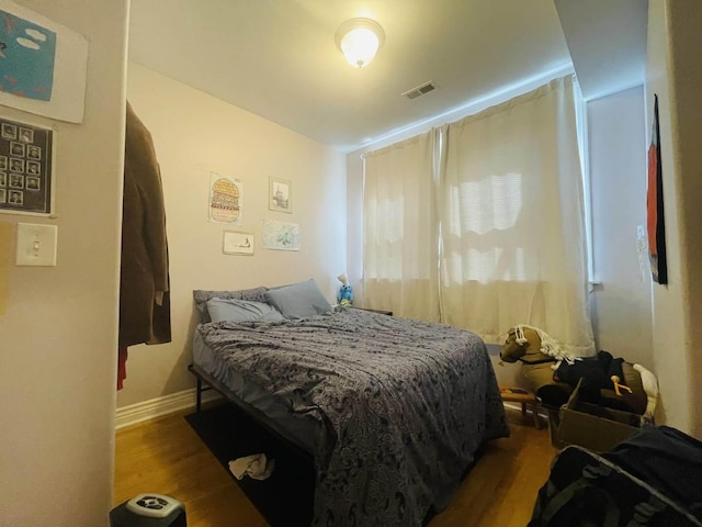 bedroom featuring baseboards, wood finished floors, and visible vents