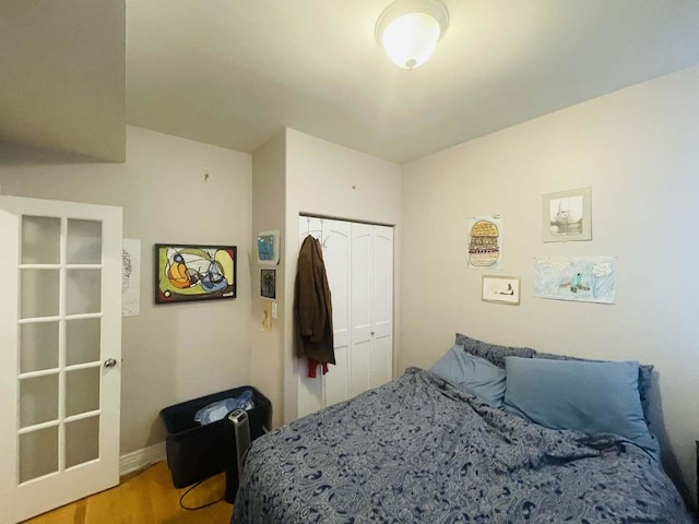 bedroom with wood finished floors, a closet, and baseboards
