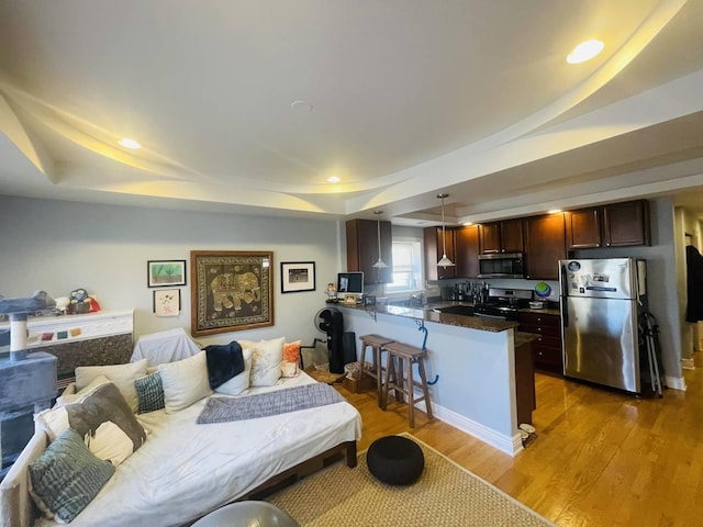 interior space featuring recessed lighting, light wood-style floors, a tray ceiling, and freestanding refrigerator