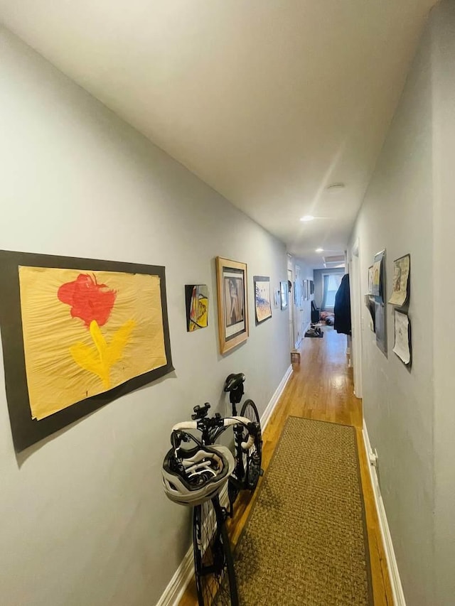 corridor with baseboards and wood finished floors