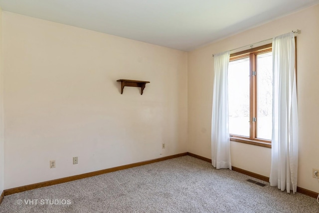 spare room with baseboards, visible vents, and light colored carpet
