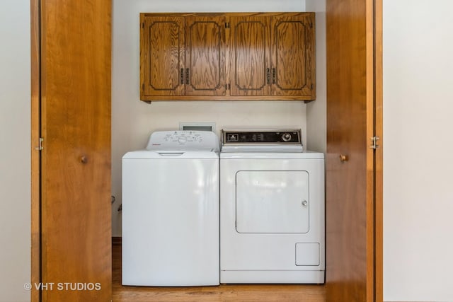 laundry room with washing machine and dryer, cabinet space, and wood finished floors