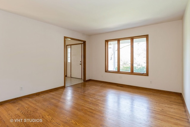 spare room featuring a healthy amount of sunlight, light wood finished floors, and baseboards