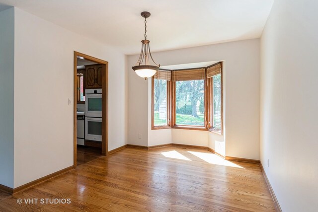 unfurnished dining area with baseboards and light wood-type flooring
