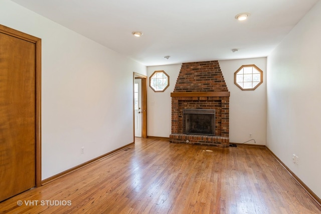 unfurnished living room with baseboards, light wood-style flooring, a fireplace, and plenty of natural light