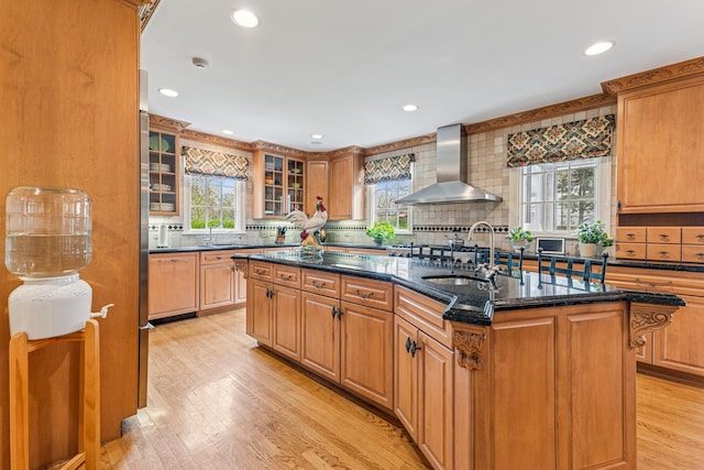 1135 Buttonwood Ln, Northbrook, IL 60062 - kitchen with a sink, wall chimney range hood, a kitchen island with sink, decorative backsplash, and light wood-style floors