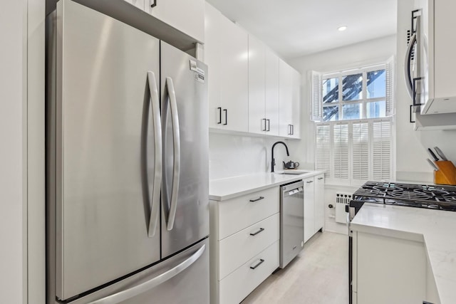 kitchen featuring white cabinets, light countertops, appliances with stainless steel finishes, and a sink