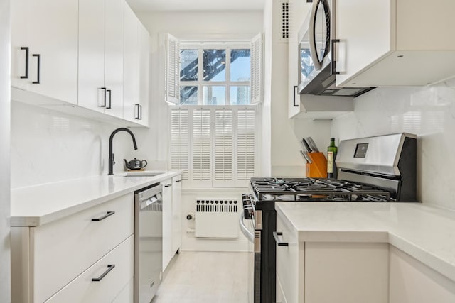 kitchen with a sink, stainless steel appliances, tasteful backsplash, light countertops, and white cabinets